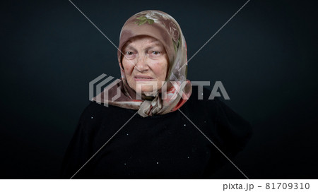 Portrait of a Turkish senior muslim woman with black background. She is nervous, tense and unhappy 81709310