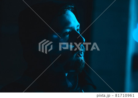 Portrait of smoking handsome man in a hood at the dark with cold blue light Portrait of smoking handsome man in a hood at the dark with cold blue light 81710961