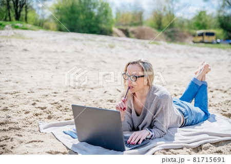 Beauty woman working at a lake, using laptop. Beauty woman working at a lake, using laptop. 81715691