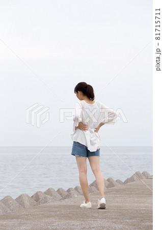夏の朝、防波堤を散歩する女性 81715711