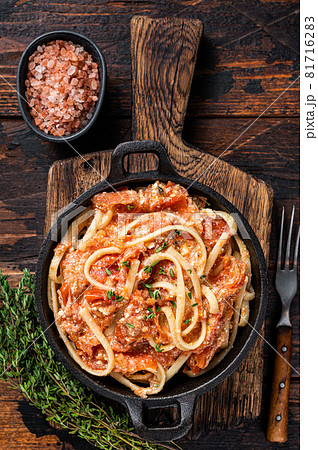 Trendy baked Feta pasta with Oven roasted tomatoes and cheese in a pan. Dark wooden background. Top view Trendy baked Feta pasta with Oven roasted tomatoes and cheese in a pan. Dark wooden background. Top view 81716283