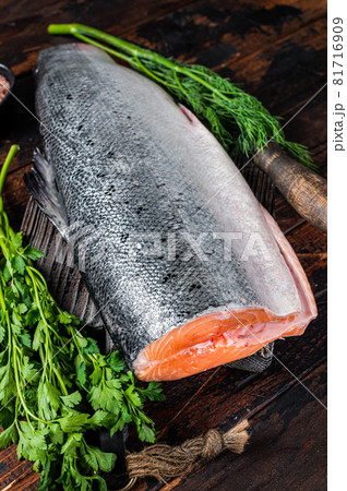 Big piece of Raw cut salmon fish on a wooden cutting board with chef knife. Dark Wooden background. Top view 81716909