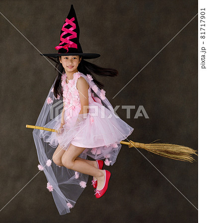 Portrait studio shot of little cute Asian kid in pink witch dress costume with black high hat look at camera posing flying gesture riding magic witchcraft broomstick on Halloween traditional festival Portrait studio shot of little cute Asian kid in pink witch dress costume with black high hat look at camera posing flying gesture riding magic witchcraft broomstick on Halloween traditional festival 81717901