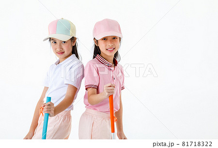 Portrait isolated studio shot of two Asian little professional girl golfers in sport fashion clothing uniform stand lean on each other back hold putter grip on green grass in front white background 81718322