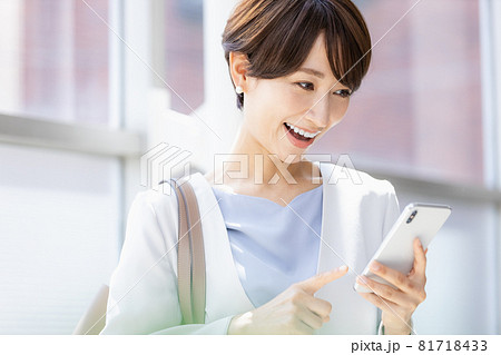 外出先でスマホのアプリを操作する女性 81718433