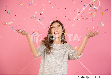 Portrait of a cheerful beautiful Asian womanl wearing dress standing standing under confetti rain and celebrating isolated over pink background Portrait of a cheerful beautiful Asian womanl wearing dress standing standing under confetti rain and celebrating isolated over pink background 81718656