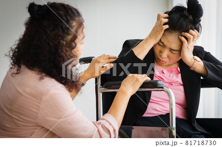 Middle age senior Asian woman take care and support female with headaches with stroke attacks on wheelchair. Concept of brain and head problem 81718730