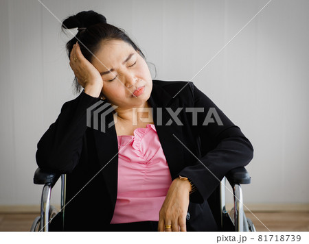Middle age senior Asian woman sitting on wheelchair feeling pain from sudden headache and brain stroke attack and hold her head with a stressed face. Concept of brain and head problem 81718739