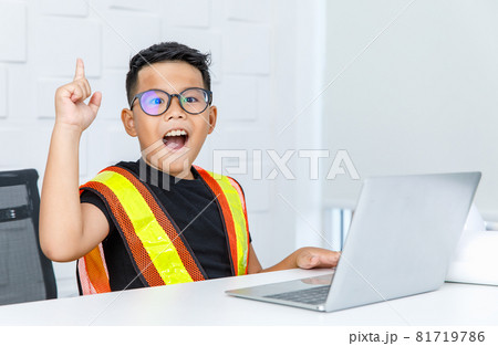 Smart Asian boy wearing glasses and yellow safety vest as foreman woking on laptop on white office desk and raising finger up with exclamation as success on finding out solution to achieve task Smart Asian boy wearing glasses and yellow safety vest as foreman woking on laptop on white office desk and raising finger up with exclamation as success on finding out solution to achieve task 81719786