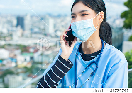 Portrait of young asian woman doctor healthcare professional in blue uniform standing in hospital.. Doctor using tablet ,mobile for work.Close up head shot on rooftop. 81720747