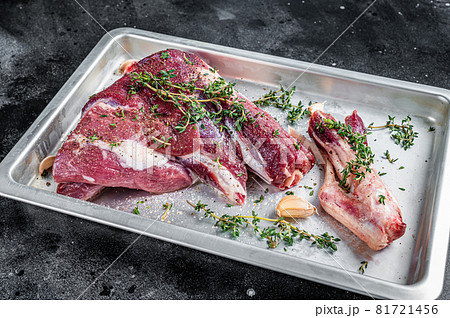 Cooking of Raw lamb mutton leg with thyme, pepper and olive oil in baking tray. Black background. Top view 81721456