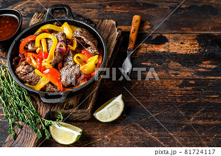 Fajitas beef meat traditional Mexican food dish in a pan. Dark wooden background. Top view. Copy space 81724117