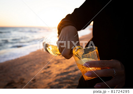 A girl pours wine at sunset on the sea A girl pours wine at sunset on the sea 81724295