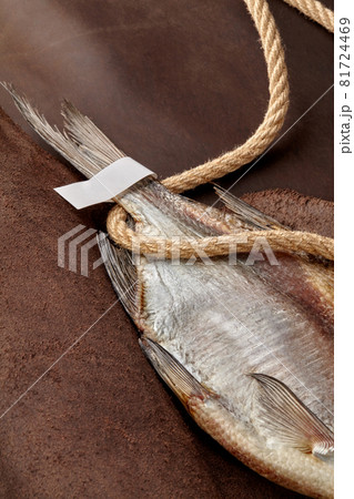 Air-dried roach tail with paper label and coarse rope on brown leather background 81724469
