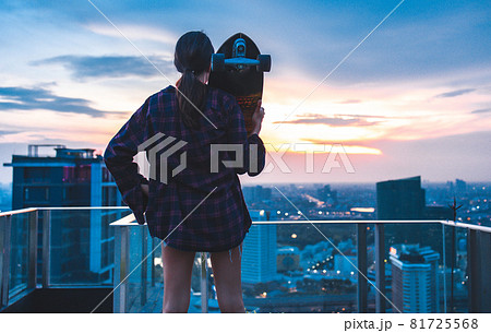 Asian young women surf skate or skates board outdoors on beautiful summer day. Happy young women play surf skate at roof top cityscape. 81725568