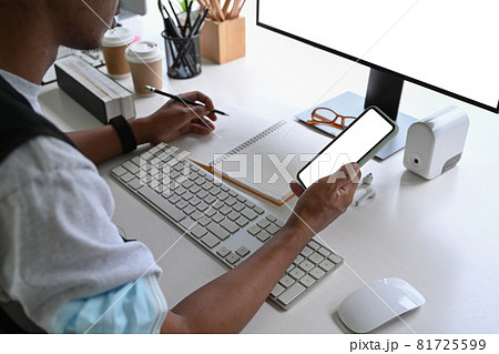 Young man using smart phone at office desk. Young man using smart phone at office desk. 81725599