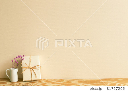 Gift box and pink dry flowers on wooden table. beige wall background Gift box and pink dry flowers on wooden table. beige wall background 81727206