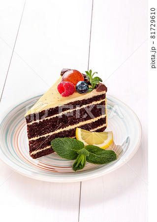 Small cake with different stuffing on a white plate. White wooden table. 81729610