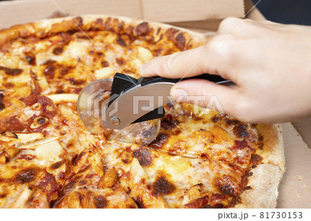 Close up on hand cutting pizza with pizza knife Tasty paperoni pizza in open box isolated on black background. Top view on paperoni pizza. Concept for italian food, street food, fast food, quick bite. 81730153