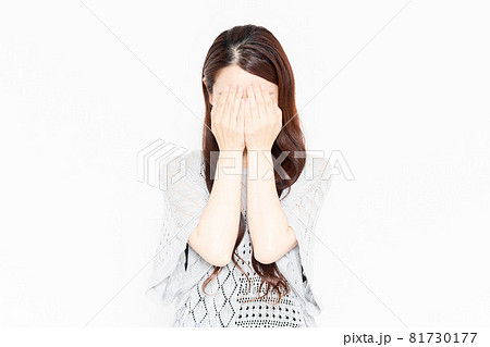 手で顔を隠しているカジュアルな服装の女性 81730177