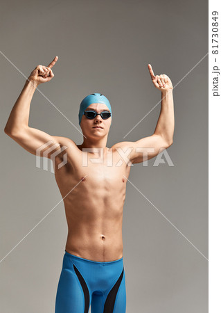 Young professional swimmer man indicates with fingers up showing a blank space. 81730849