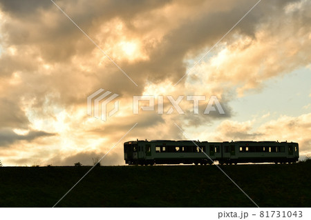 北杜市小淵沢町、夕焼雲の下を行く小海線列車。ヘッドライト 81731043