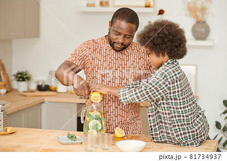 Cute little boy squeezing lemon juice into jug with lemonade Cute little boy squeezing lemon juice into jug with lemonade 81734937