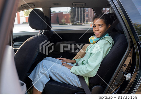 Happy youthful girl looking at you with smile from backseat of car 81735158