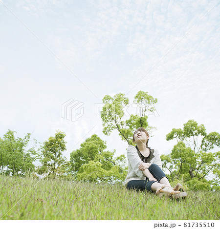 草原に座って空を見上げる女性 81735510
