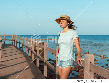 Teen girl standing on wooden bridge by the sea Teen girl standing on wooden bridge by the sea 81736122