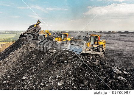 Yellow excavator in career moves overburden. Bulldozer combs the ground, with the bright sun and nice blue sky in the background 81736997