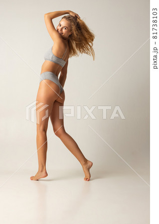 Side view full-length portrait of young caucasian woman in gray inner wear isolated over white studio background Side view full-length portrait of young caucasian woman in gray inner wear isolated over white studio background 81738103