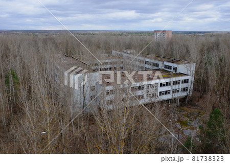 An abandoned concrete building among the trees in Pripyat. Aerial view. Cloudy weather, landscape. An abandoned concrete building among the trees in Pripyat. Aerial view. Cloudy weather, landscape. 81738323