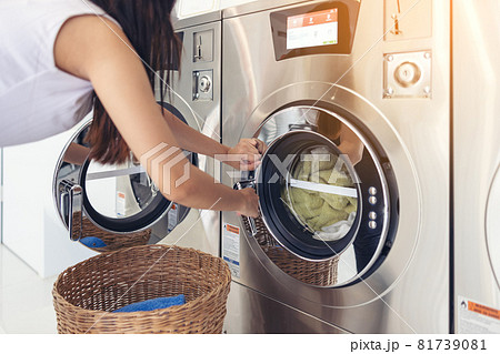 At a laundromat shop with many automatic washing machines, a beautiful woman wearing a mask is doing laundry. At a laundromat shop with many automatic washing machines, a beautiful woman wearing a mask is doing laundry. 81739081