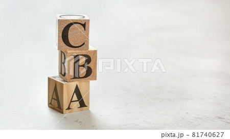 Pile with three wooden cubes - letters CBA meaning Cost Benefit Assessment on them, space for more text / images at right side. 81740627