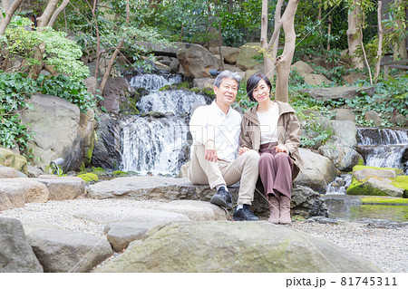 シニア夫婦旅行 滝をバックに思い出を語る仲の良い夫婦 81745311