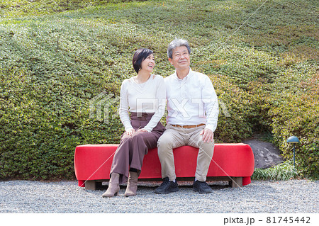 シニア夫婦旅行 長椅子に座り思い出を語る仲の良い夫婦 81745442