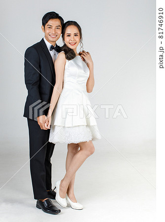Young attractive Asian couple, bride and groom, woman wearing white wedding dress. Man wearing black tuxedo, standing together. Concept for pre wedding photography 81746910