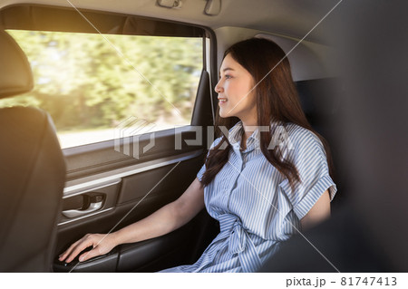 woman thinking and looking view out of window while sitting in the back seat of car 81747413