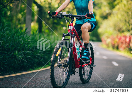 Woman cycling on tropical park trail in summer Woman cycling on tropical park trail in summer 81747653