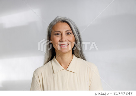 Portrait of pretty grey haired woman in beige blouse on light background Portrait of pretty grey haired woman in beige blouse on light background 81747847