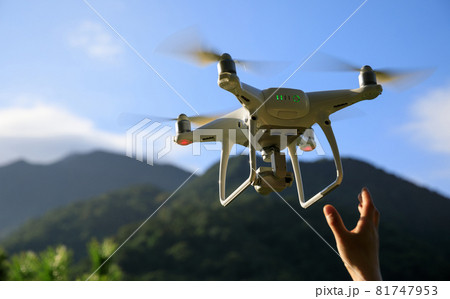 Hand reaching for a flying drone in summer forest 81747953