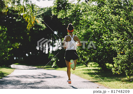 Fitness woman running on sunny tropical park trail 81748209