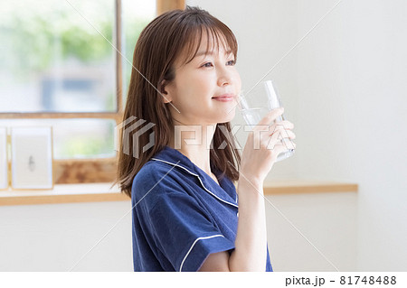 パジャマ姿でミネラルウォーターを飲む若い女性 81748488