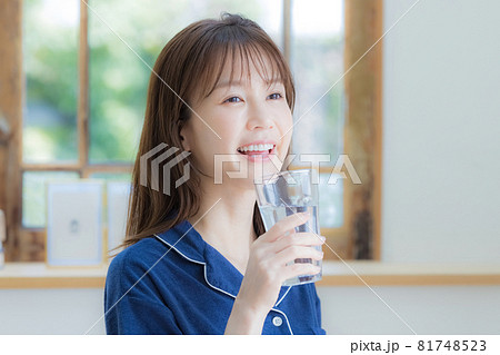 パジャマ姿でミネラルウォーターを飲む若い女性 81748523