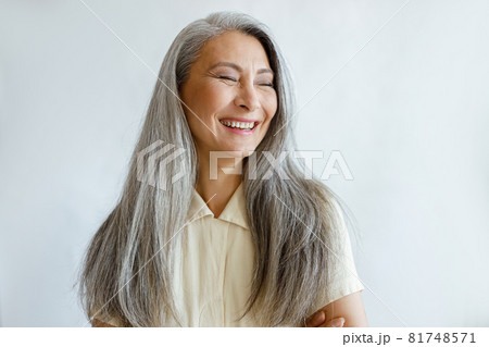 Portrait of smiling Asian woman with hoary hair and crossed arms on grey background Portrait of smiling Asian woman with hoary hair and crossed arms on grey background 81748571