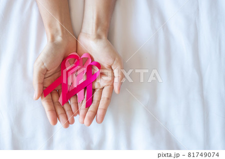 October Breast Cancer Awareness month, adult Woman  hand holding Pink Ribbon on pink background for supporting people living and illness. International Women, Mother and World cancer day concept 81749074