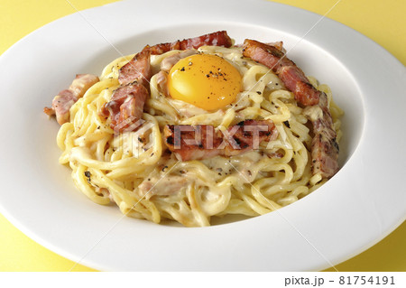 カリカリに焼いた厚切りベーコン入りのカルボナーラに卵黄トッピング 81754191