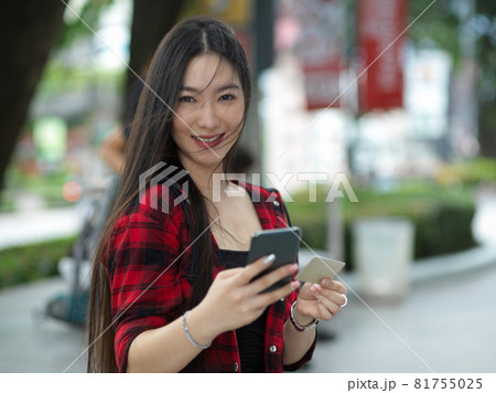 Attractive beautiful millennial woman with smartphone and credit card in hands 81755025