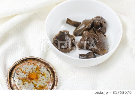 Botulism, the danger of food poisoning by canned food concept. Unsuitable marinated mushrooms in a white ceramic bowl. Rusty tin lid with black stains. Homemade pickled Suillus. 81758070